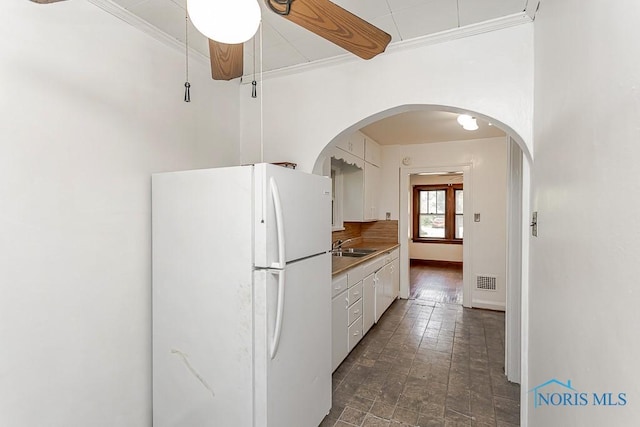 2529 Greenbriar Rd, Toledo, OH 43607 - kitchen featuring freestanding refrigerator, ornamental molding, white cabinetry, arched walkways, and a ceiling fan