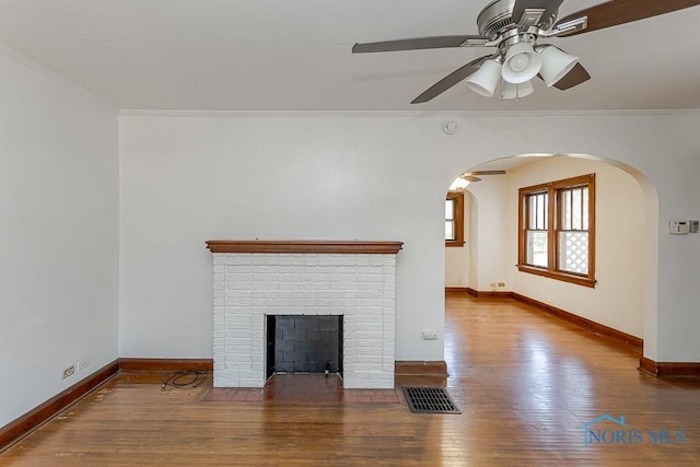 2529 Greenbriar Rd, Toledo, OH 43607 - unfurnished living room with a ceiling fan, arched walkways, wood-type flooring, crown molding, and a brick fireplace