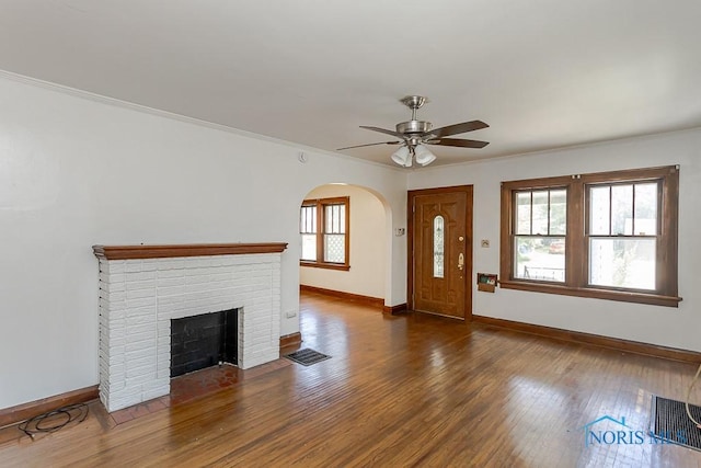 2529 Greenbriar Rd, Toledo, OH 43607 - unfurnished living room featuring a ceiling fan, arched walkways, ornamental molding, wood finished floors, and a brick fireplace