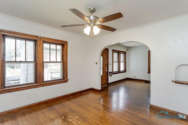2529 Greenbriar Rd, Toledo, OH 43607 - empty room featuring arched walkways, dark wood-style floors, plenty of natural light, and crown molding