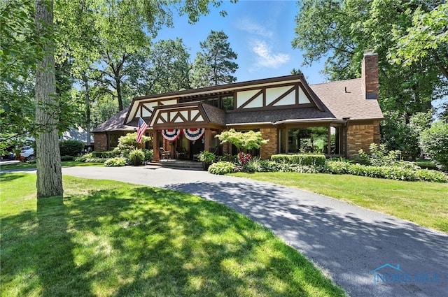 4567 Torquay Ave, Toledo, OH 43615 - tudor home featuring a front yard, a chimney, brick siding, and curved driveway