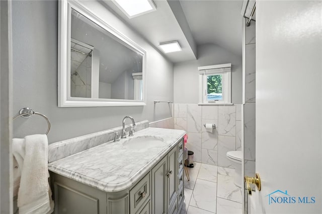 4567 Torquay Ave, Toledo, OH 43615 - full bathroom with marble finish flooring, vanity, tile walls, a wainscoted wall, and lofted ceiling