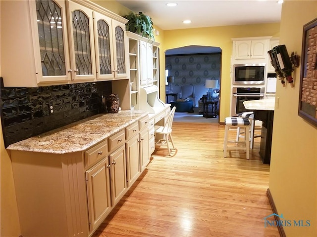 3704 Brookside Rd, Ottawa Hills, OH 43606 - kitchen featuring stainless steel appliances, light wood finished floors, tasteful backsplash, glass insert cabinets, and recessed lighting