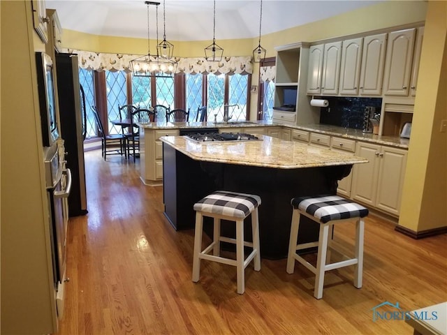 3704 Brookside Rd, Ottawa Hills, OH 43606 - kitchen featuring stainless steel gas cooktop, a peninsula, light wood-style floors, a breakfast bar area, and pendant lighting