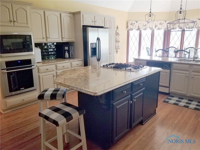 3704 Brookside Rd, Ottawa Hills, OH 43606 - kitchen with stainless steel appliances, blue cabinets, a center island, light wood-type flooring, and vaulted ceiling