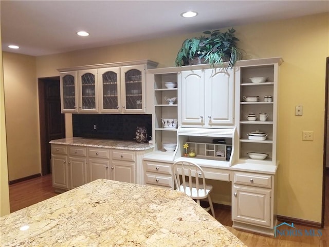 3704 Brookside Rd, Ottawa Hills, OH 43606 - kitchen with open shelves, wood finished floors, glass insert cabinets, recessed lighting, and light stone counters