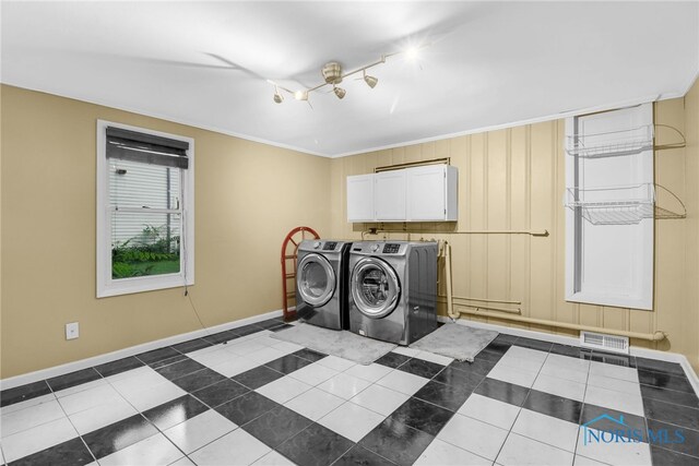 545 Wallace Ave, Bowling Green, OH 43402 - laundry room featuring washer and dryer, cabinet space, dark tile patterned floors, and crown molding
