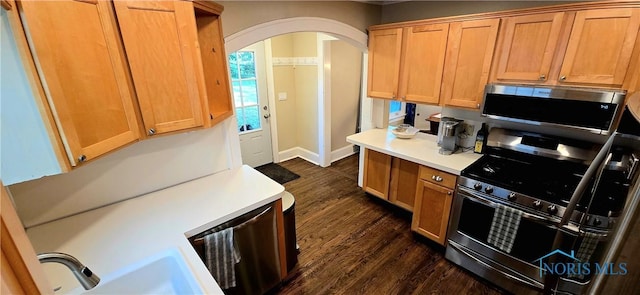 3329 Kirkwall Rd, Ottawa Hills, OH 43606 - kitchen featuring appliances with stainless steel finishes, arched walkways, dark wood finished floors, and light countertops