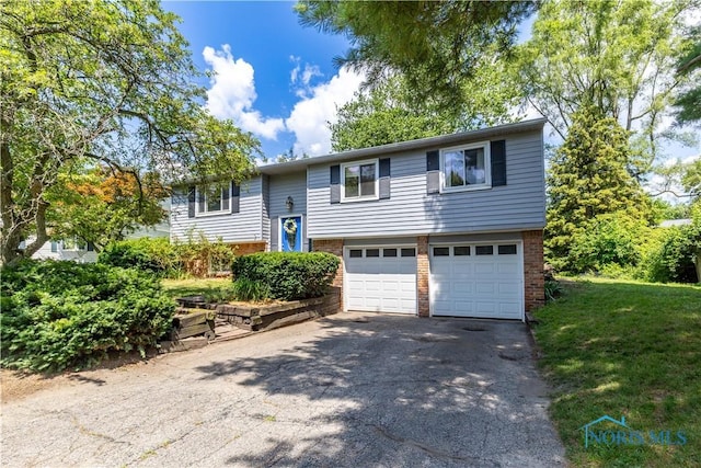 6768 Denbridge Dr, Sylvania, OH 43560 - bi-level home featuring a garage, brick siding, and asphalt driveway