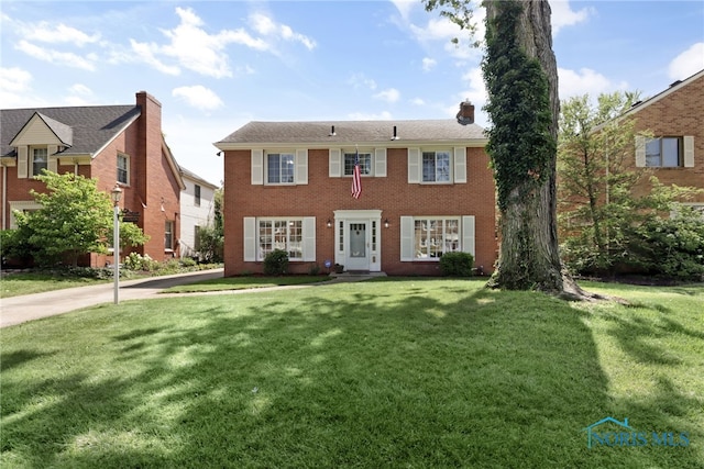 2310 Goddard Rd, Toledo, OH 43606 - colonial house featuring a front lawn, a chimney, and brick siding
