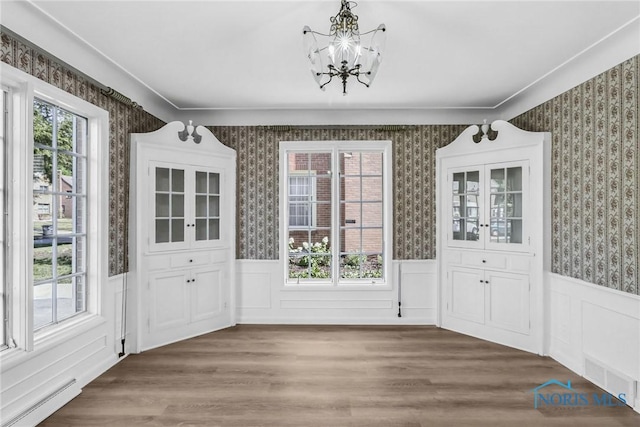 2310 Goddard Rd, Toledo, OH 43606 - unfurnished dining area featuring a baseboard heating unit, a chandelier, wallpapered walls, wainscoting, and wood finished floors