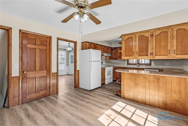 2310 Goddard Rd, Toledo, OH 43606 - kitchen with white appliances, under cabinet range hood, a peninsula, light countertops, and brown cabinetry