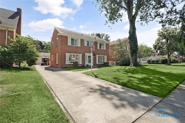 2310 Goddard Rd, Toledo, OH 43606 - colonial home with driveway, a front lawn, brick siding, and a chimney