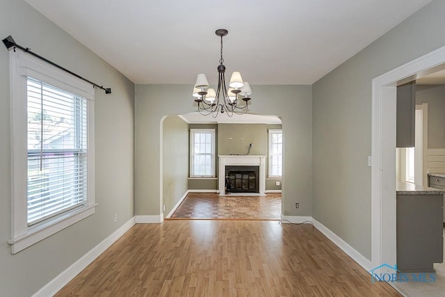 4334 Commonwealth Ave, Toledo, OH 43612 - unfurnished living room with wood finished floors, arched walkways, a chandelier, and a fireplace with flush hearth