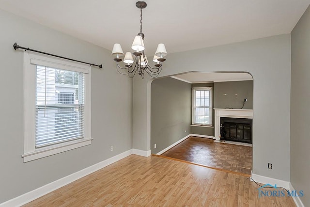 4334 Commonwealth Ave, Toledo, OH 43612 - unfurnished living room featuring wood finished floors, a chandelier, arched walkways, and a fireplace with flush hearth