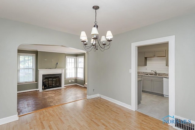 4334 Commonwealth Ave, Toledo, OH 43612 - unfurnished living room featuring arched walkways, plenty of natural light, a chandelier, and light wood-style flooring