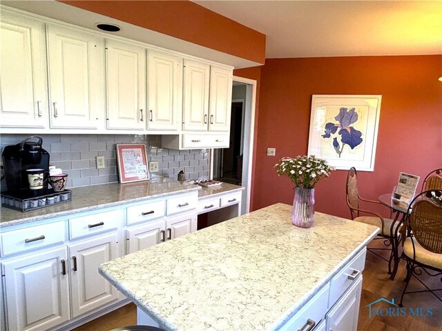 7361 Caracole Ct Unit 7361, Sylvania, OH 43560 - kitchen with white cabinetry, backsplash, a center island, light stone countertops, and dark wood-style flooring