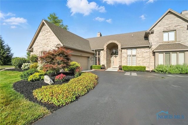 5576 N Citation Rd, Ottawa Hills, OH 43615 - french country inspired facade featuring a chimney, a garage, asphalt driveway, stone siding, and roof with shingles