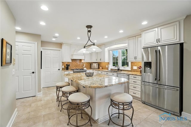 5576 N Citation Rd, Ottawa Hills, OH 43615 - kitchen featuring stainless steel appliances, decorative backsplash, a center island, light stone counters, and recessed lighting