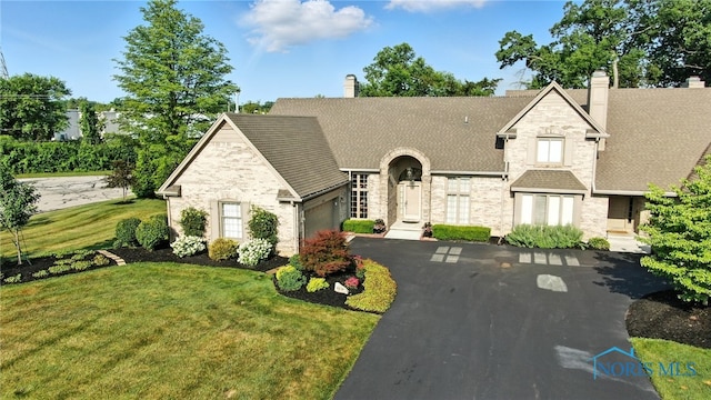 5576 N Citation Rd, Ottawa Hills, OH 43615 - view of front of home featuring stone siding, a garage, asphalt driveway, and a chimney