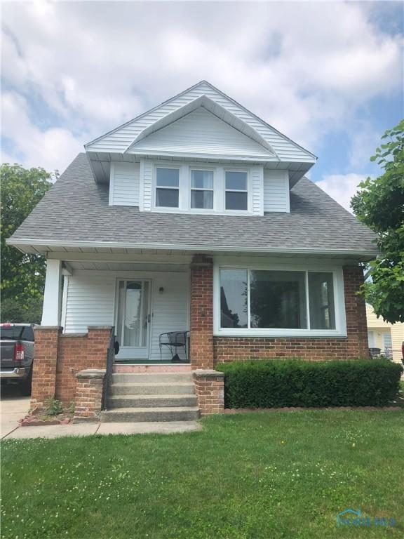 4815 298th St, Toledo, OH 43611 - bungalow-style home with a porch, a front lawn, and brick siding