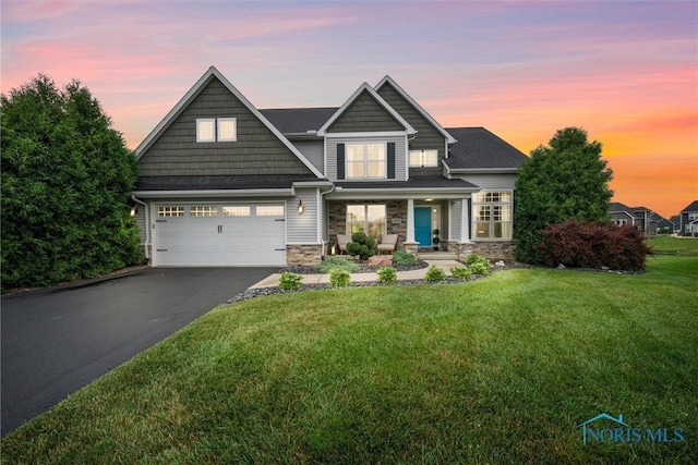 9258 Nate Ct, Sylvania, OH 43560 - view of front of home with asphalt driveway, stone siding, a lawn, covered porch, and an attached garage