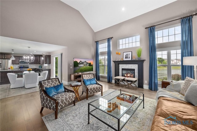 9258 Nate Ct, Sylvania, OH 43560 - living room with high vaulted ceiling, a chandelier, a tiled fireplace, and light wood-style flooring