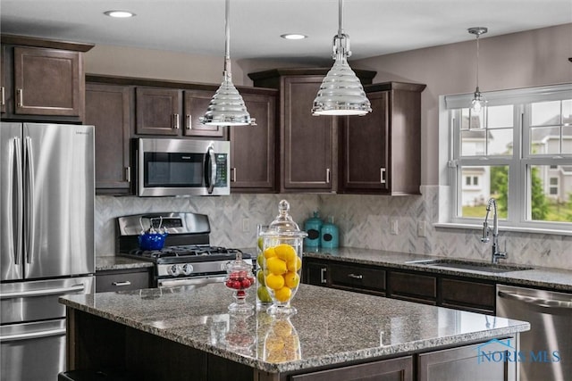 9258 Nate Ct, Sylvania, OH 43560 - kitchen featuring stainless steel appliances, dark brown cabinets, stone counters, a center island, and hanging light fixtures