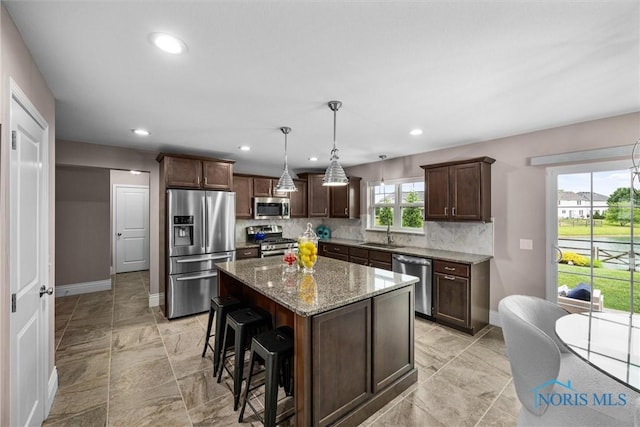9258 Nate Ct, Sylvania, OH 43560 - kitchen featuring appliances with stainless steel finishes, backsplash, dark brown cabinets, light stone countertops, and a kitchen bar