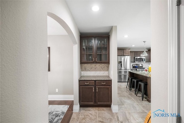 9258 Nate Ct, Sylvania, OH 43560 - bar area with stainless steel appliances, decorative backsplash, arched walkways, recessed lighting, and light tile patterned floors