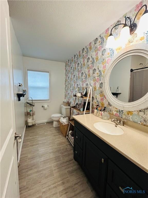 1020 Fremont Ave, Findlay, OH 45840 - bathroom with vanity, wallpapered walls, a textured ceiling, and a shower with curtain
