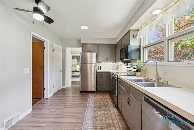 1673 Watova Rd, Toledo, OH 43614 - kitchen with appliances with stainless steel finishes, gray cabinetry, light countertops, and light wood-style flooring