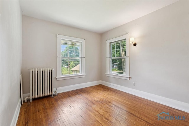 1673 Watova Rd, Toledo, OH 43614 - empty room with radiator heating unit, plenty of natural light, and hardwood / wood-style floors