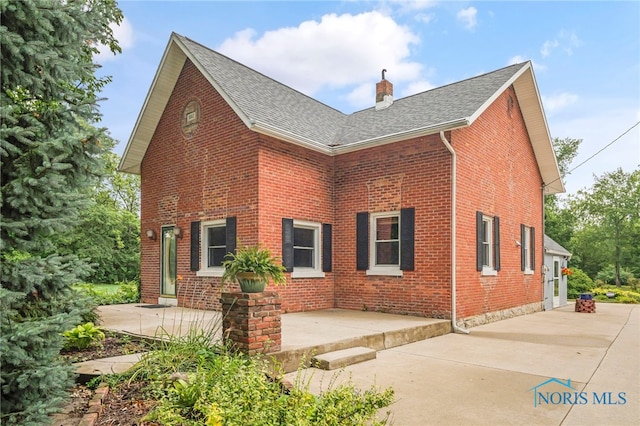 21010 Lemoyne Rd, Luckey, OH 43443 - view of front of home with a chimney, brick siding, a shingled roof, and a patio
