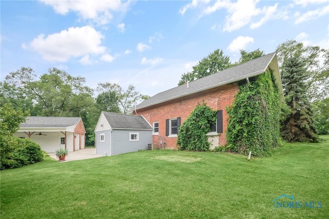 21010 Lemoyne Rd, Luckey, OH 43443 - rear view of property featuring brick siding, a lawn, an outbuilding, roof with shingles, and a ceiling fan