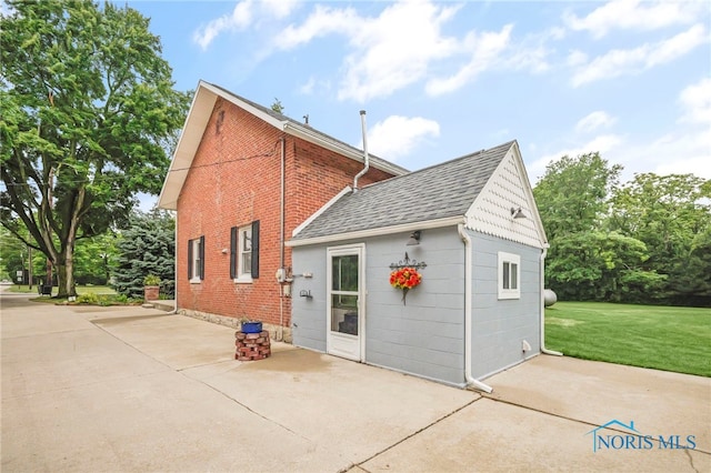 21010 Lemoyne Rd, Luckey, OH 43443 - rear view of property with brick siding, a patio area, a lawn, and roof with shingles