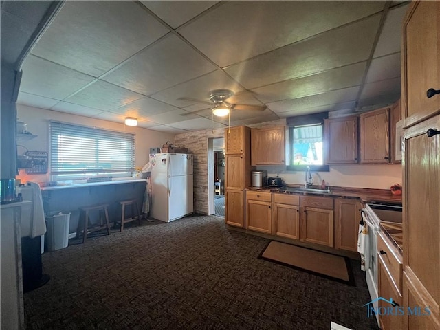 8872 Rd 87, Paulding, OH 45879 - kitchen with freestanding refrigerator, a drop ceiling, dark countertops, healthy amount of natural light, and dark carpet