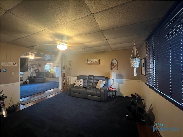 8872 Rd 87, Paulding, OH 45879 - living room with a ceiling fan, a paneled ceiling, carpet flooring, arched walkways, and wainscoting