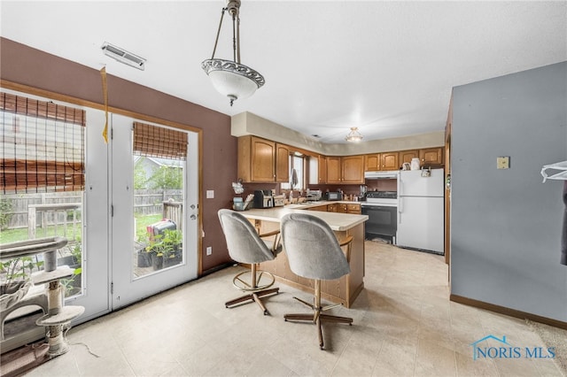 304 Fulton St, Fayette, OH 43521 - kitchen featuring freestanding refrigerator, range with electric stovetop, a peninsula, light countertops, and brown cabinets