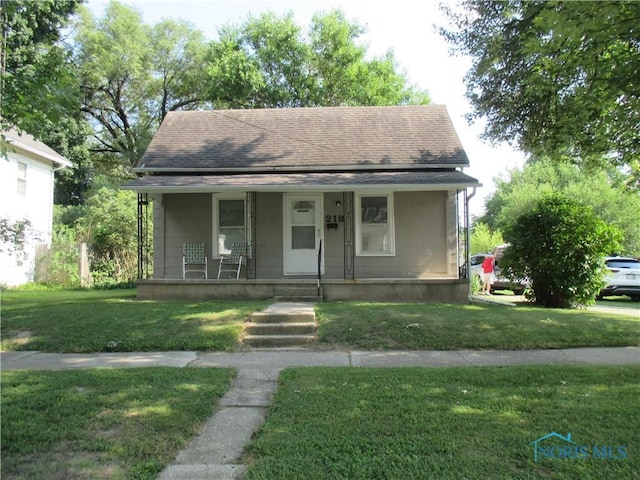 218 Cherry St, Wauseon, OH 43567 - bungalow-style house with a porch, a front lawn, and roof with shingles