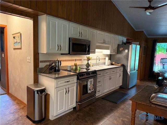 19445 Powers Rd, Defiance, OH 43512 - kitchen with appliances with stainless steel finishes, vaulted ceiling, wooden walls, a ceiling fan, and white cabinetry