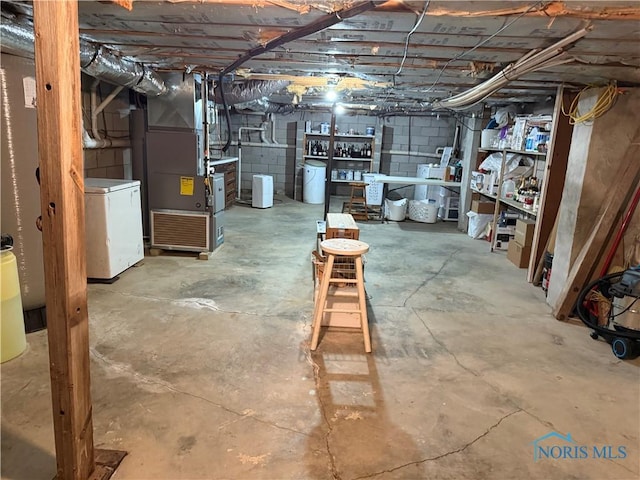 19445 Powers Rd, Defiance, OH 43512 - unfinished below grade area with heating unit, fridge, and concrete block wall