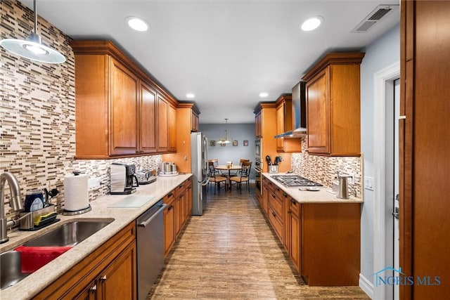 3605 W Laskey Rd, Toledo, OH 43623 - kitchen with stainless steel appliances, wall chimney range hood, light wood-type flooring, brown cabinetry, and decorative backsplash