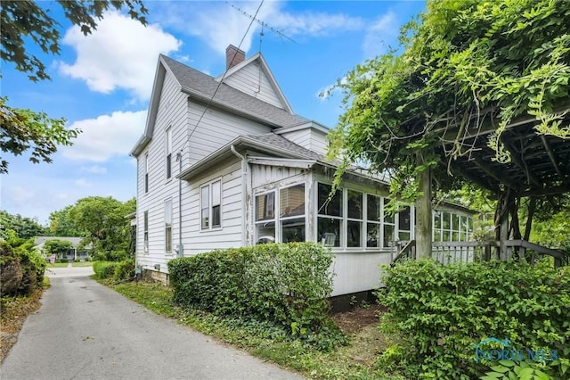 2008 N Main St, Findlay, OH 45840 - view of side of home with a chimney, a sunroom, and a shingled roof