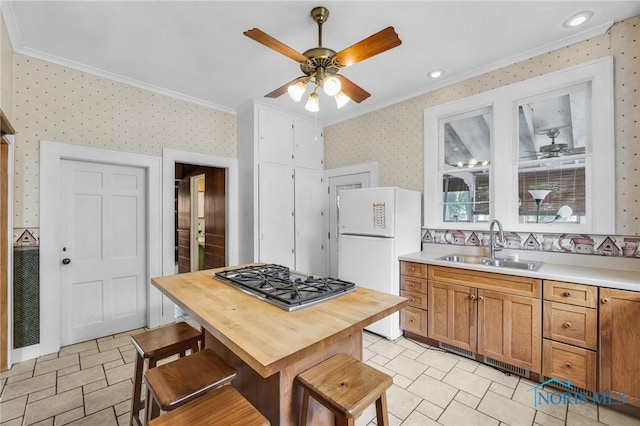 2008 N Main St, Findlay, OH 45840 - kitchen with crown molding, freestanding refrigerator, stainless steel gas stovetop, a ceiling fan, and wallpapered walls