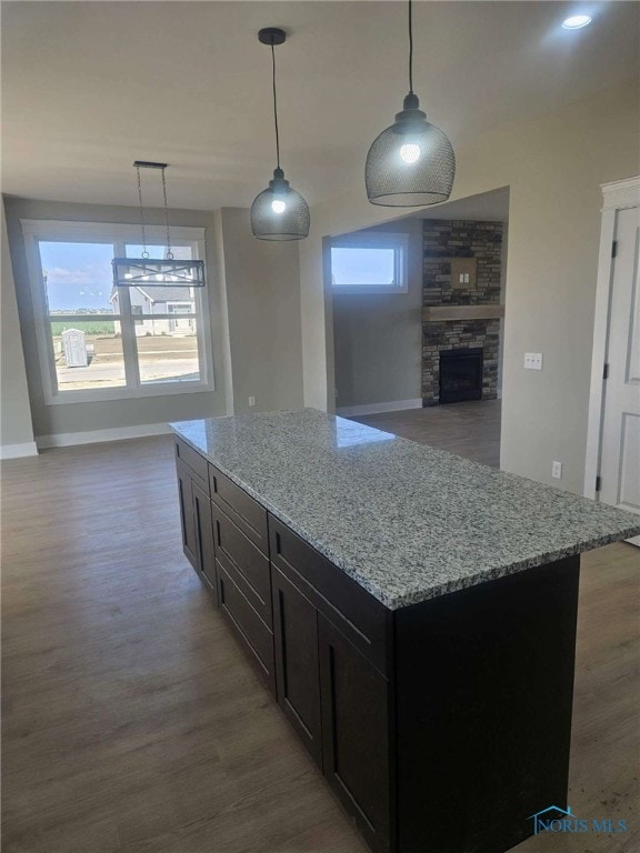 6332 Pimlico Rd, Whitehouse, OH 43571 - kitchen with wood finished floors, light stone countertops, a stone fireplace, and hanging light fixtures