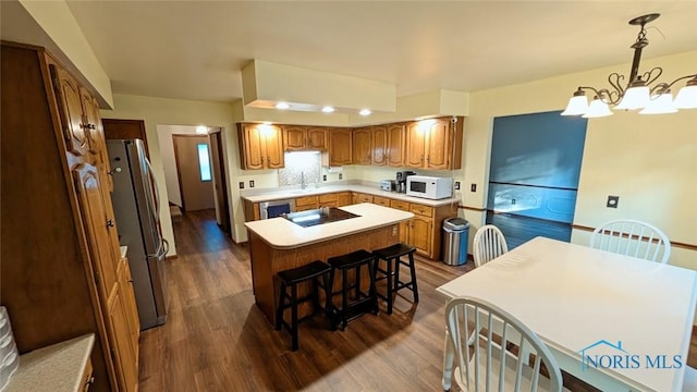 2359 Cheshire Woods Rd, Toledo, OH 43617 - kitchen featuring white microwave, freestanding refrigerator, a chandelier, a center island, and dark wood finished floors
