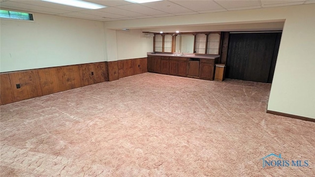 2359 Cheshire Woods Rd, Toledo, OH 43617 - empty room with a drop ceiling, light carpet, a wainscoted wall, bar with sink, and wooden walls