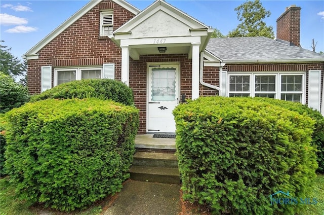 1447 Craigwood Rd, Toledo, OH 43612 - view of front of home with brick siding, a chimney, and a shingled roof