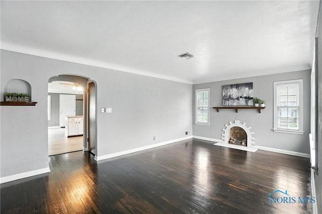 1447 Craigwood Rd, Toledo, OH 43612 - unfurnished living room with arched walkways, dark wood finished floors, and a fireplace with flush hearth